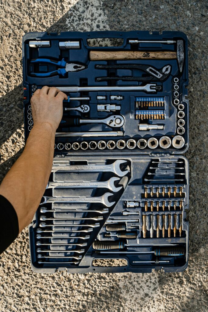 Close-up of a toolbox with various tools, hand interacting, outdoor setting.