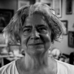 A serene black and white portrait capturing the essence of a smiling senior woman indoors.