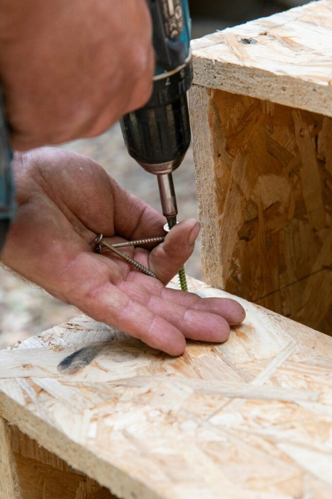 Detailed image of a worker drilling screws into wooden boards.